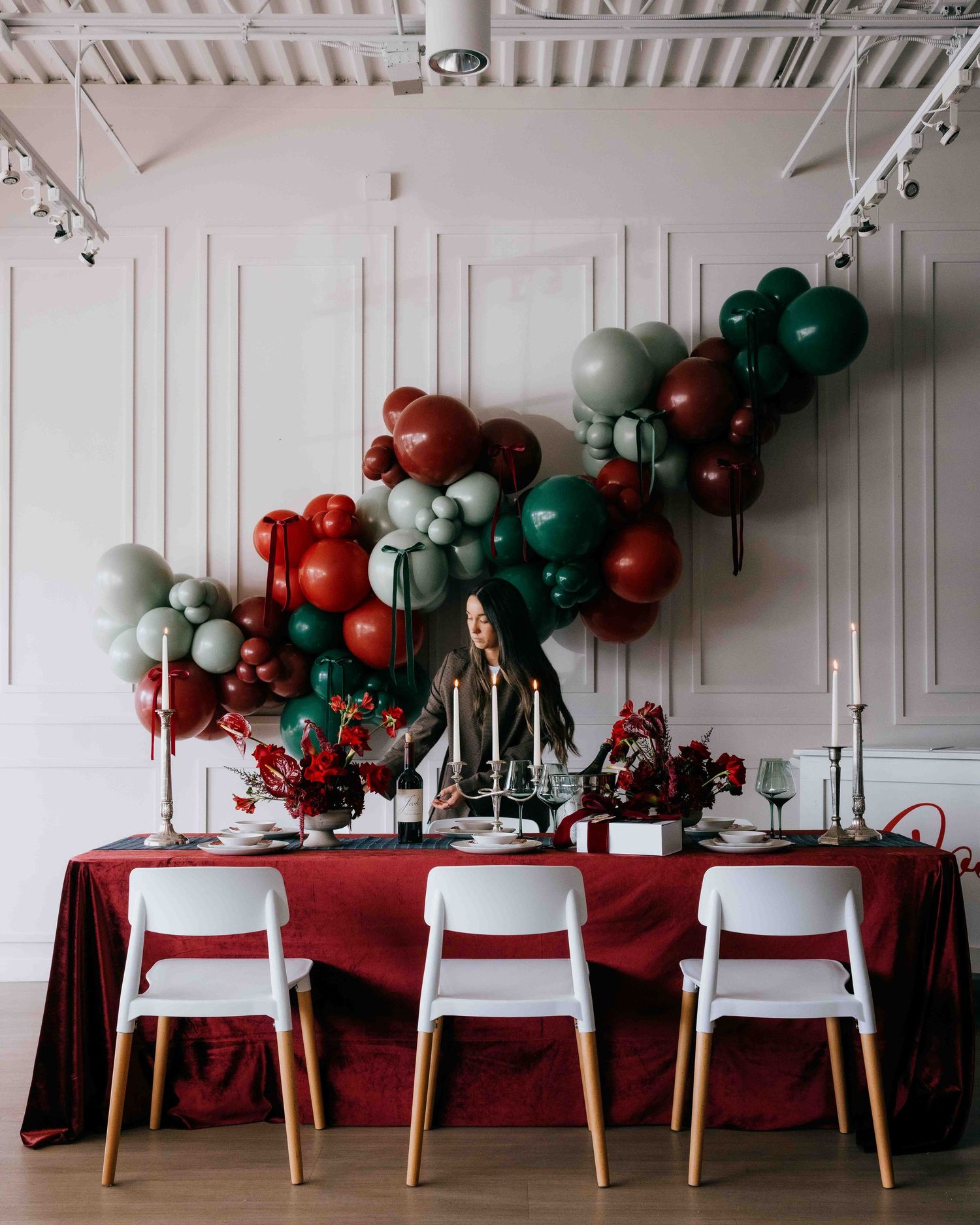 The founder of Palm Events & Rentals staging a table for an event with bouquets of flowers, elaborate table settings, and elegant ballooons.