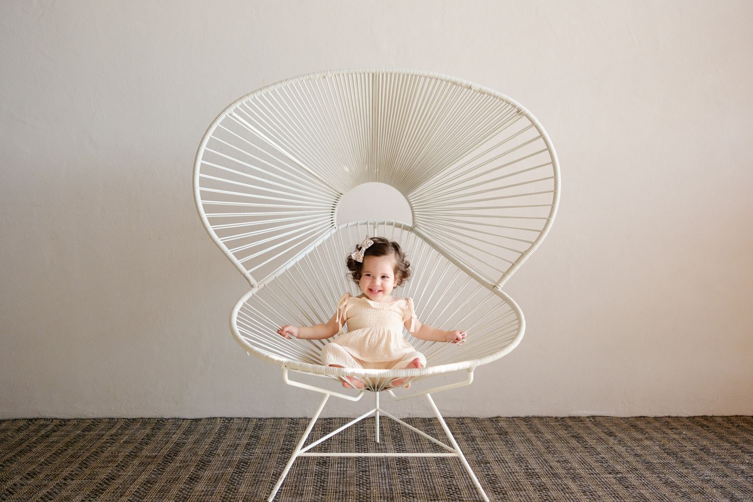 A white Acapulco chair photographed from multiple angles against a neutral wall shows its iconic curved design.