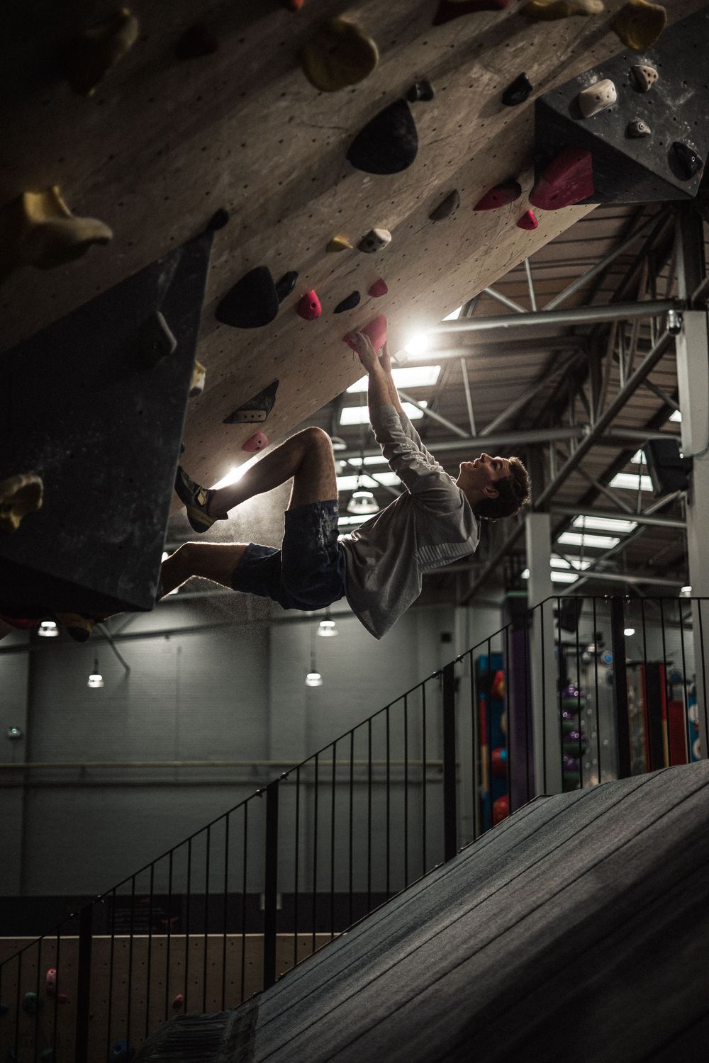 An indoor rock climbing wall with colorful holds and dramatic lighting.