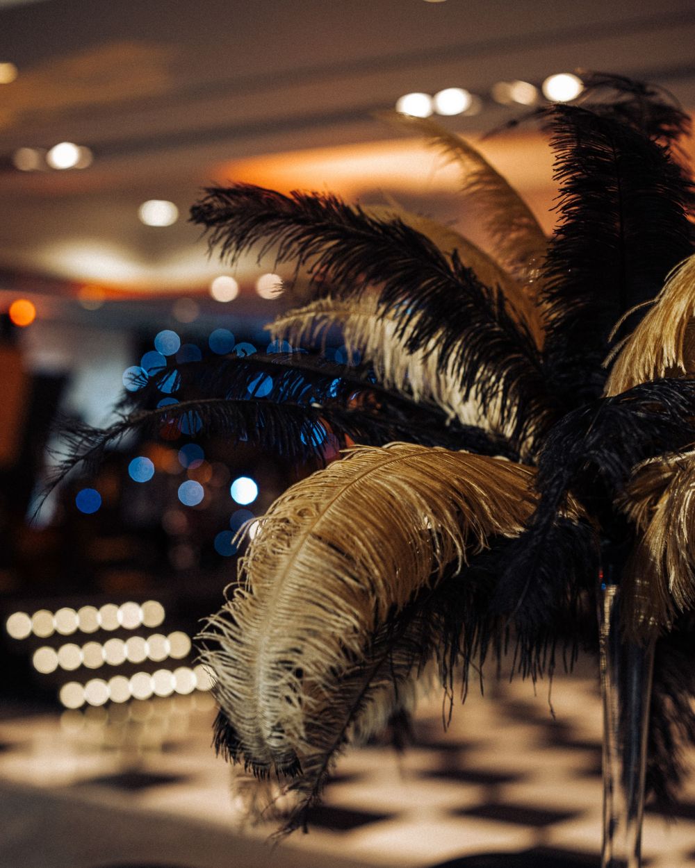Black ostrich feather centerpieces silhouetted against soft bokeh lighting at an elegant event.