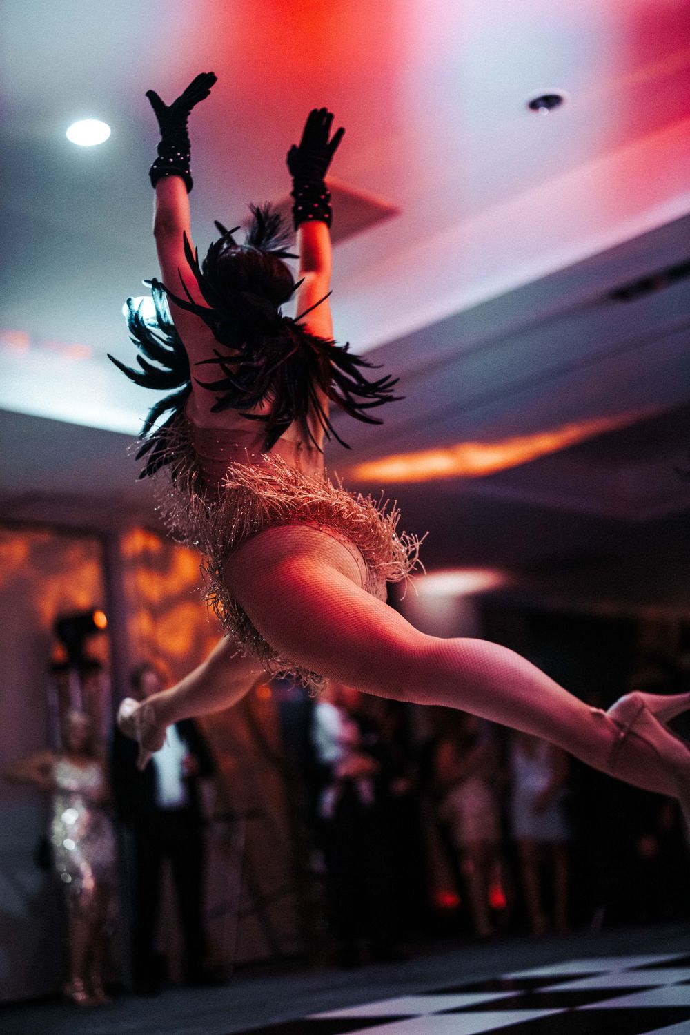 A dramatic silhouette of a dancer leaping through red-lit stage atmosphere.