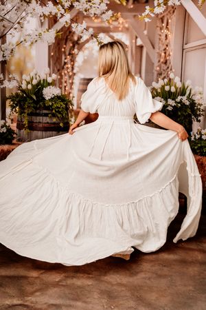 A sequence of photos showing a white cotton dress flowing and twirling in motion against a rustic backdrop.