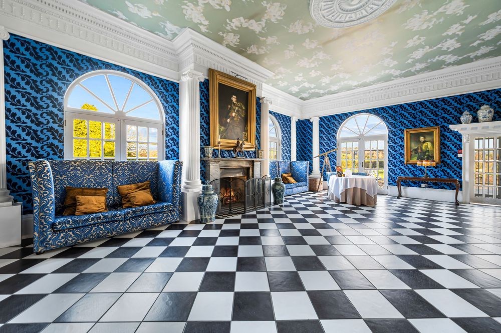 Elegant interior hallway with black and white checkered floor, blue damask wallpaper, and ornate white crown molding.