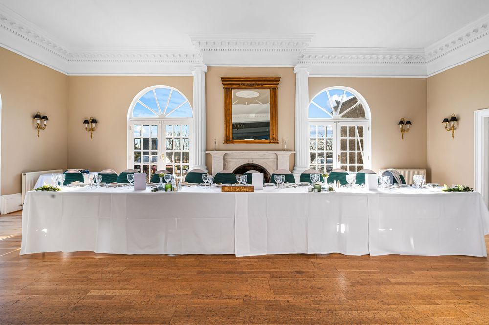 Elegant ballroom interior with white walls, crown molding, hardwood floors and arched windows in natural light.