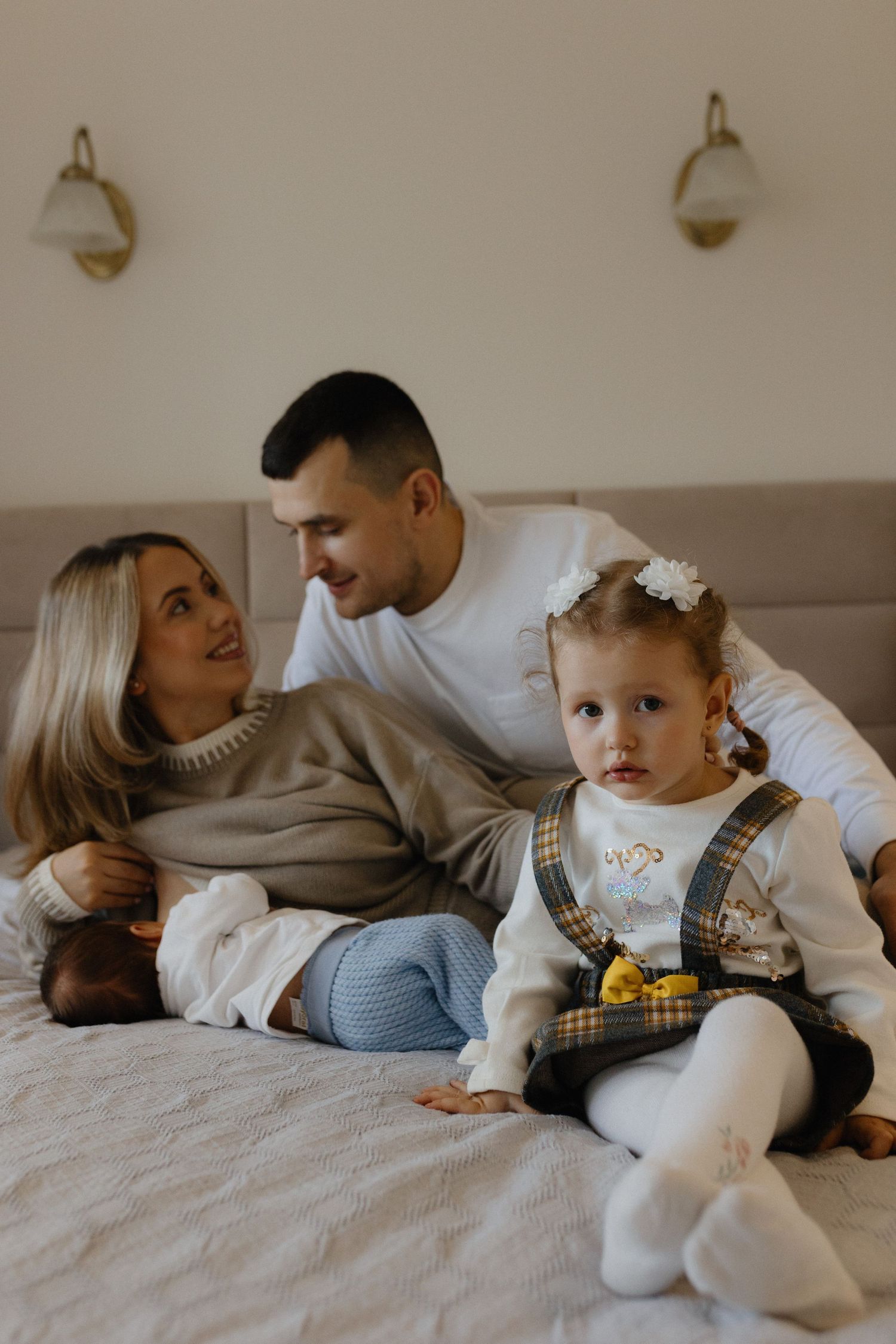 A tender family moment captured in a series of intimate photographs showing parents embracing their baby in a bright room.