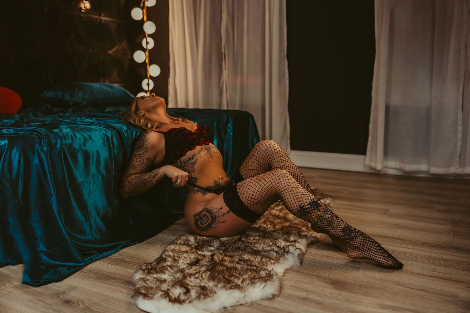 Intimate boudoir photo with teal bedding and dramatic lighting.