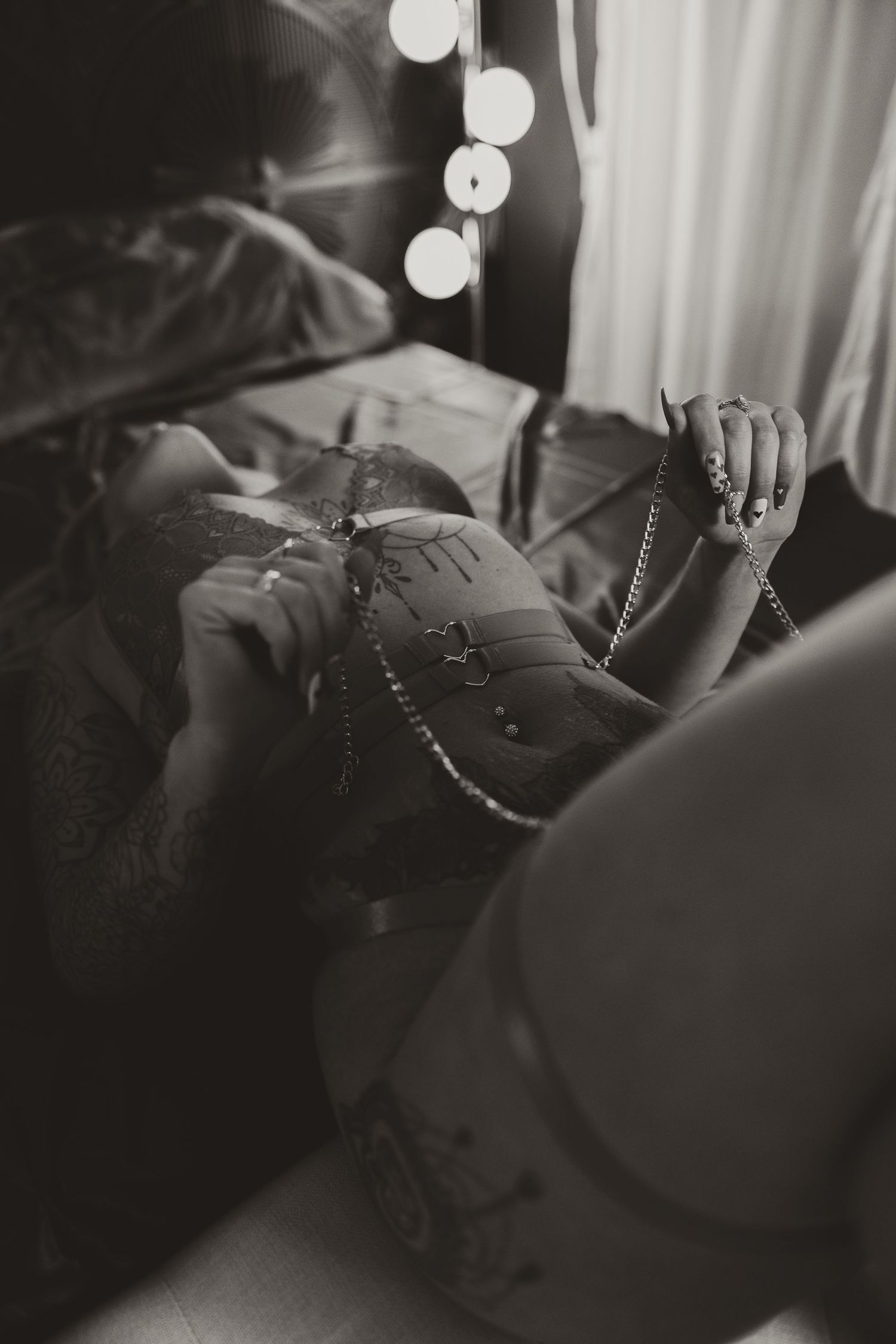 Intimate black and white boudoir photo with string lights and delicate details.