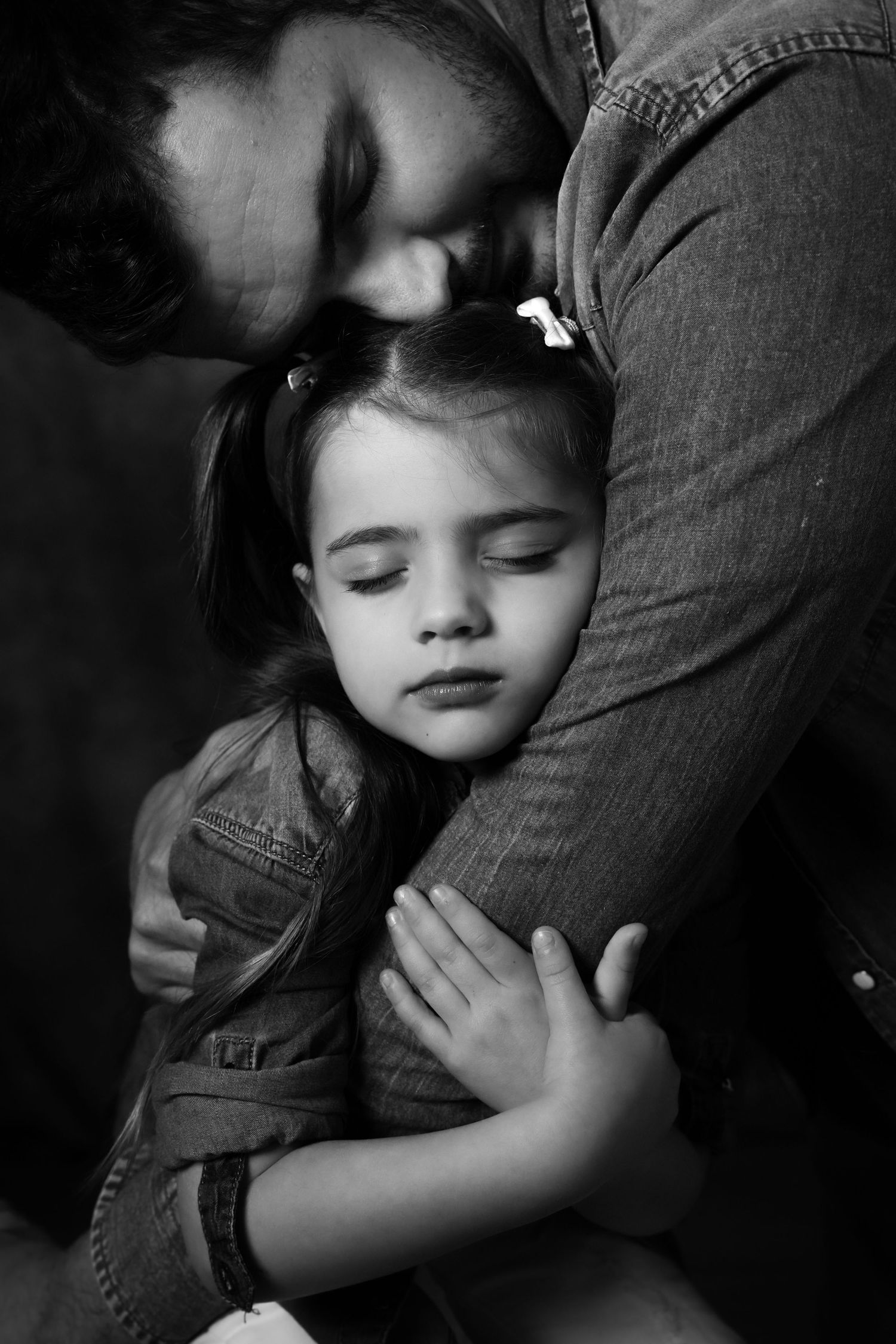 Papà che abbraccia la figlia addormentata in un ritratto fotografico padre e figlia in studio a Sanremo
