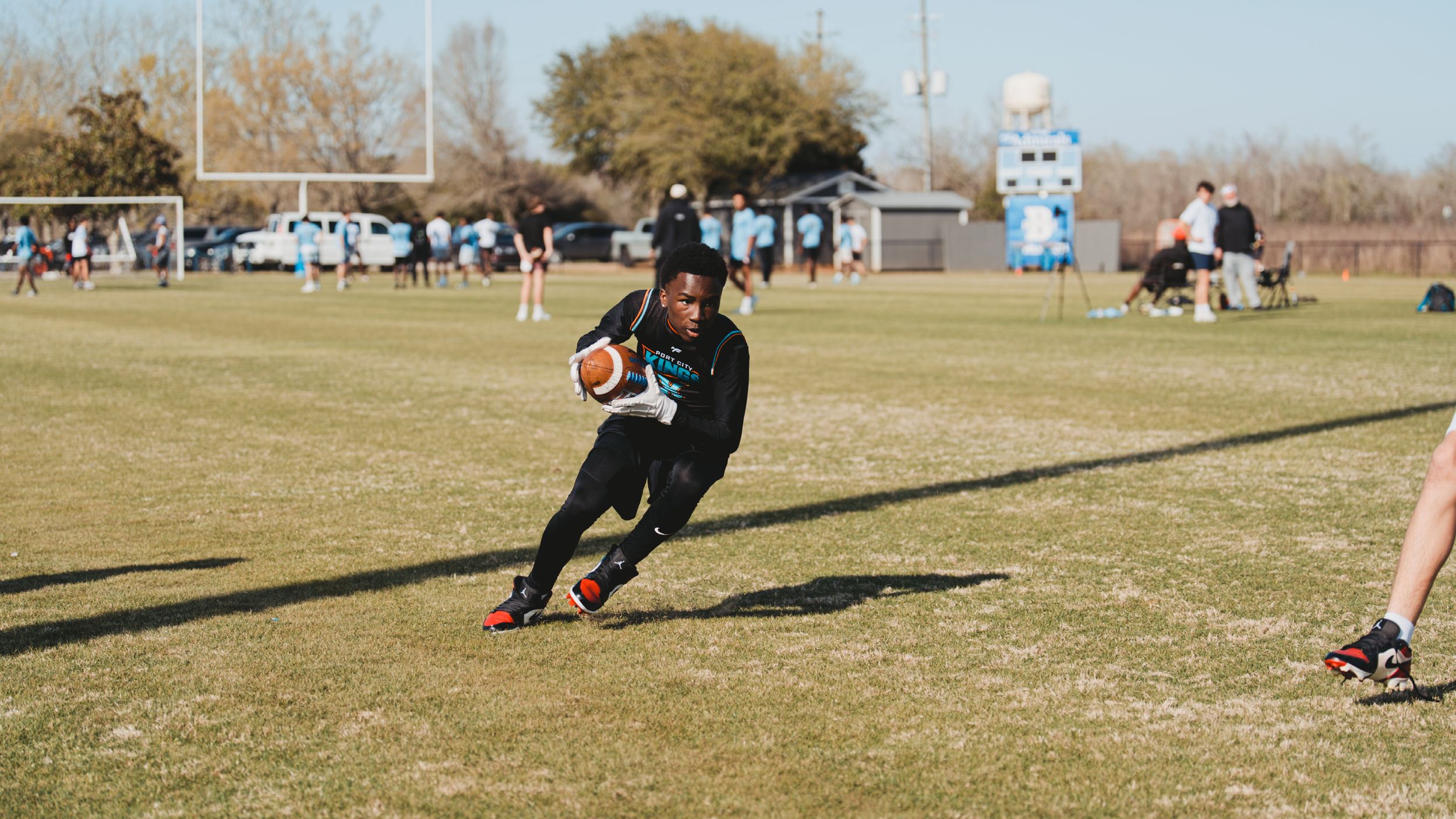 Rugby player runs with ball across grass field during daytime match.