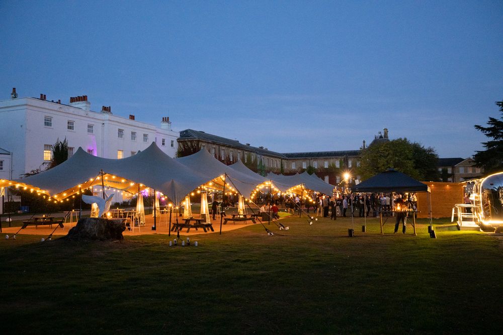A white event tent illuminated at dusk with string lights and decorations creating a warm, festive atmosphere.