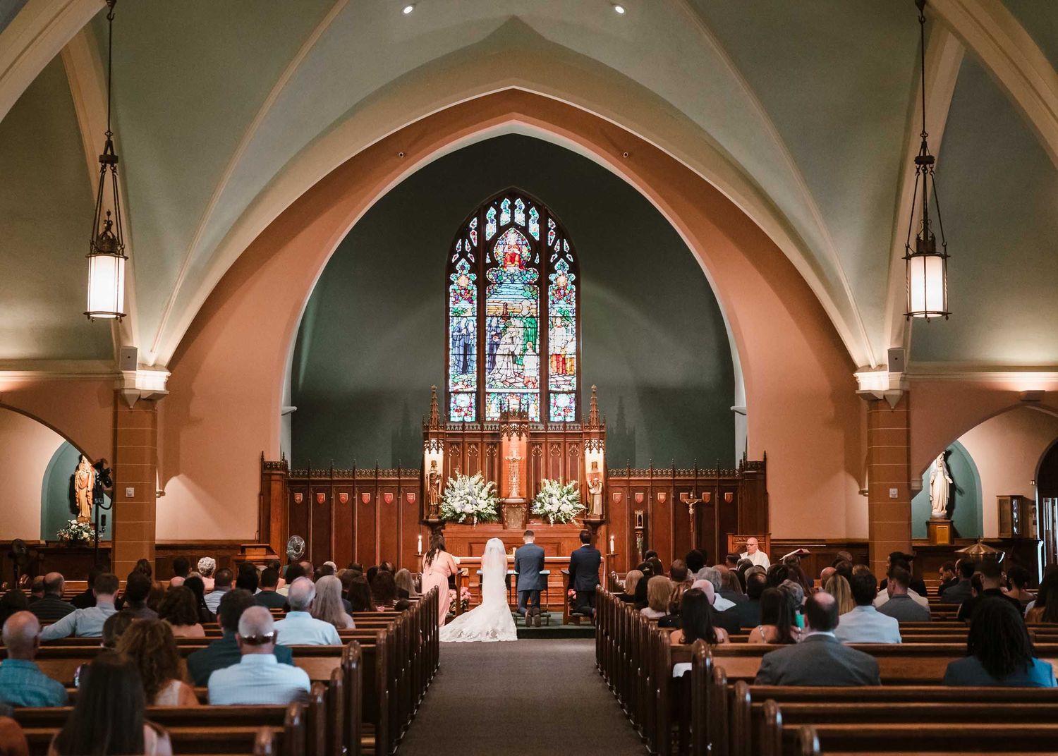 Wide view of wedding ceremony at Saint Brigid Church in South Boston with bride and groom at the altar