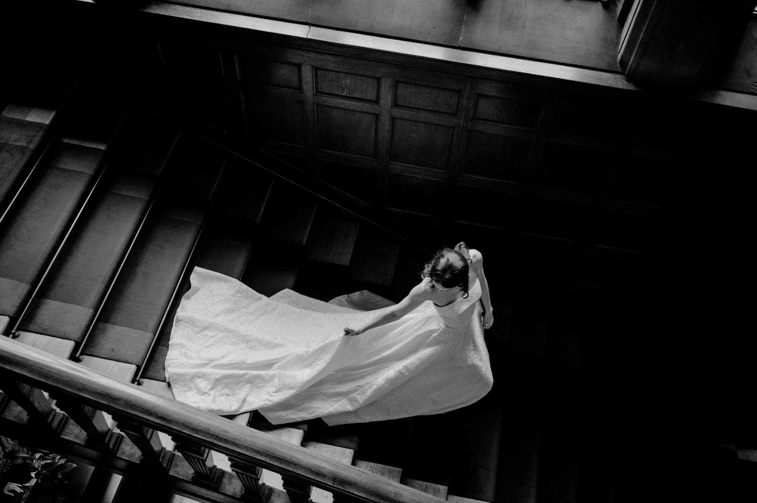 eine braut läuft in ihrem brautkleid die treppe hinunter. bild in schwarz weiß