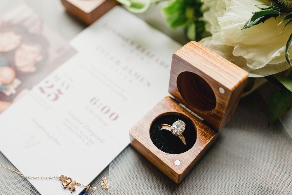 Close-up of wedding rings in wooden boxes with floral decorations.