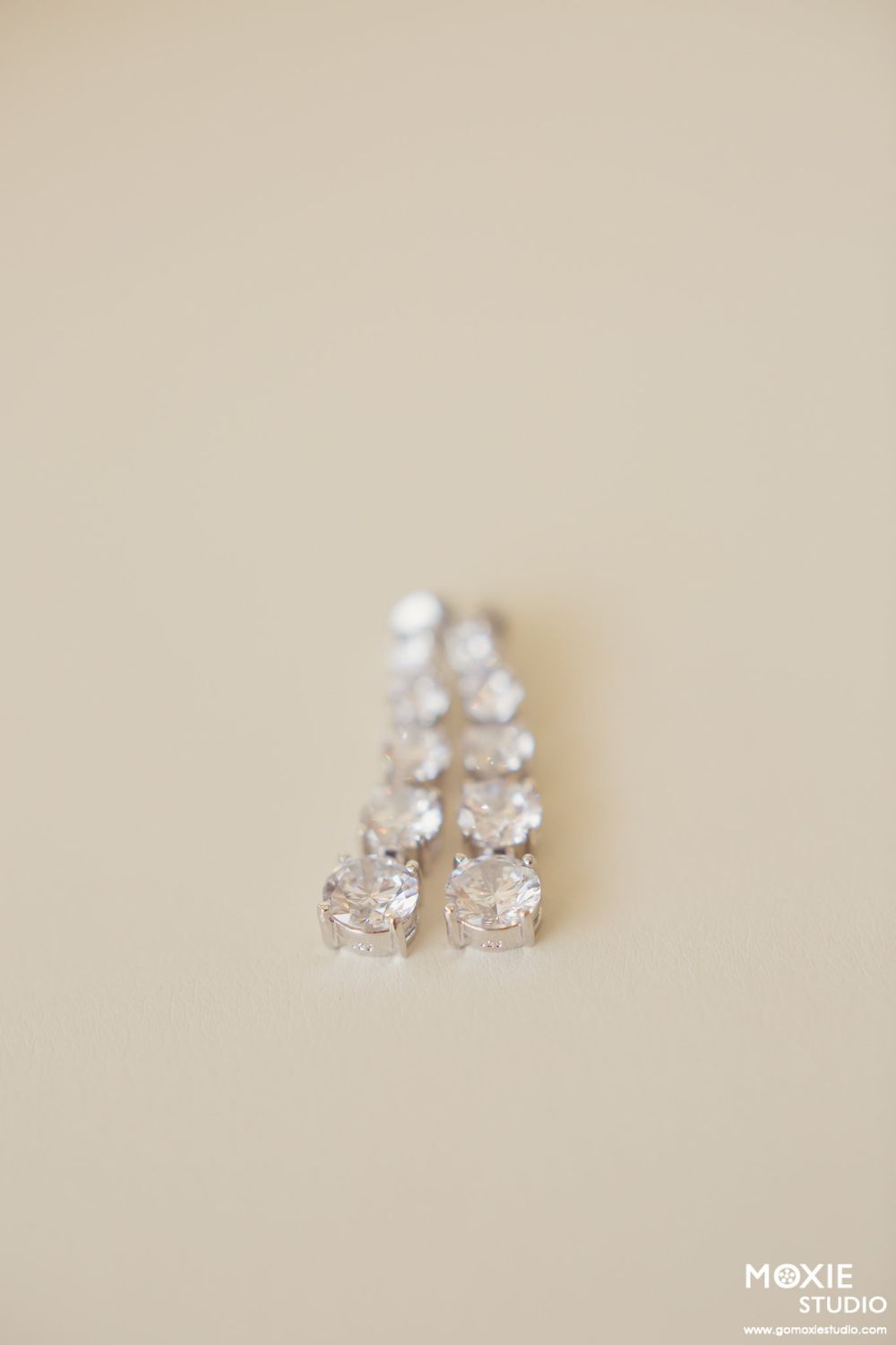 Delicate crystal earrings arranged on a cream-colored background.