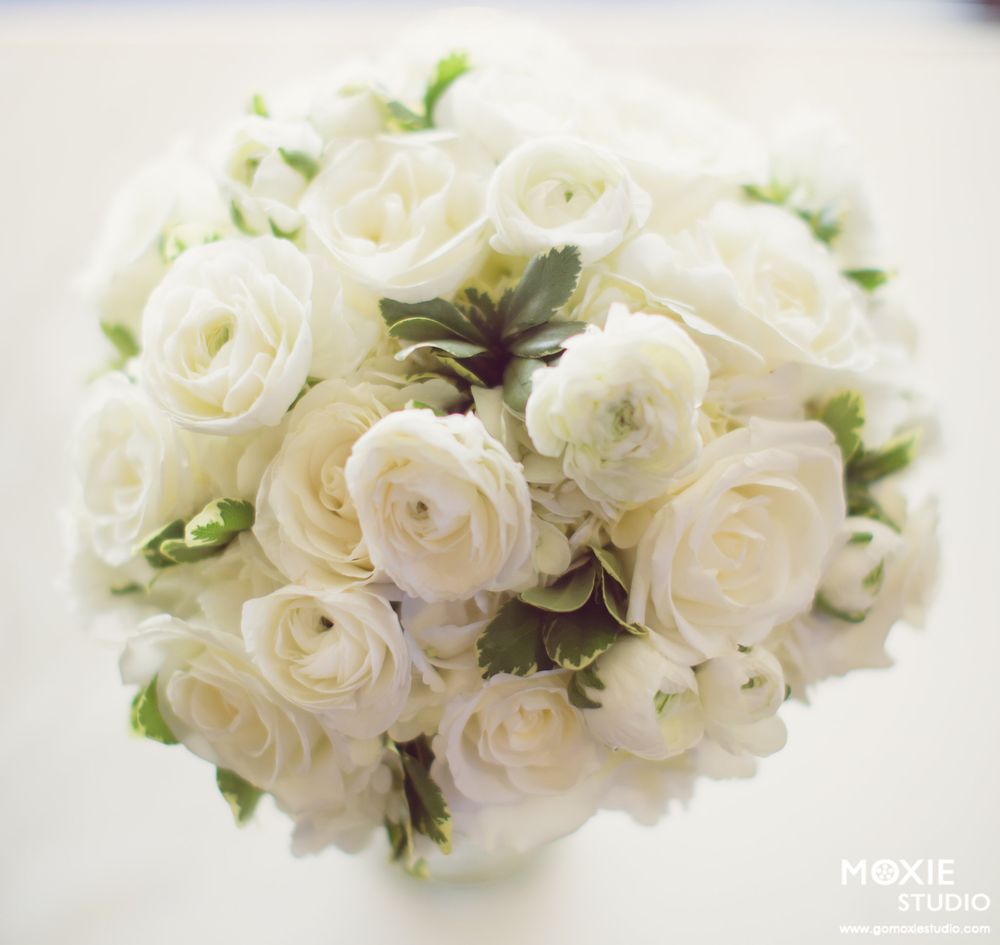 Elegant white rose and ranunculus bridal bouquet with delicate greenery accents arranged in a classic style.