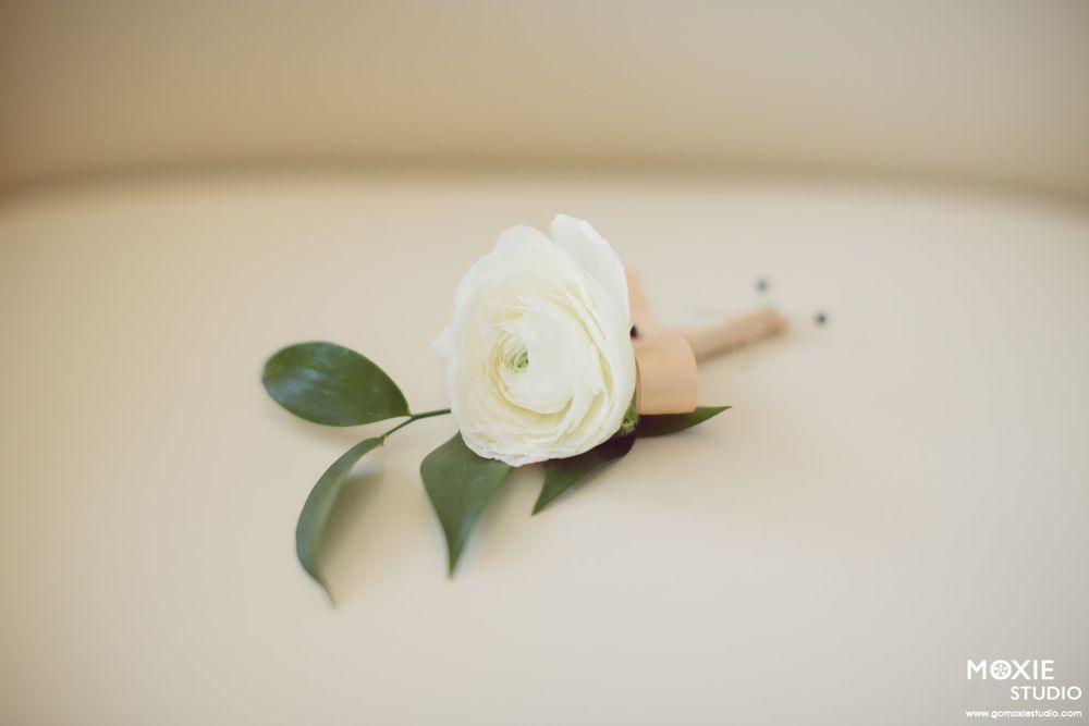 Delicate white rose and green foliage arrangements create an elegant wedding decor detail against a soft neutral background.