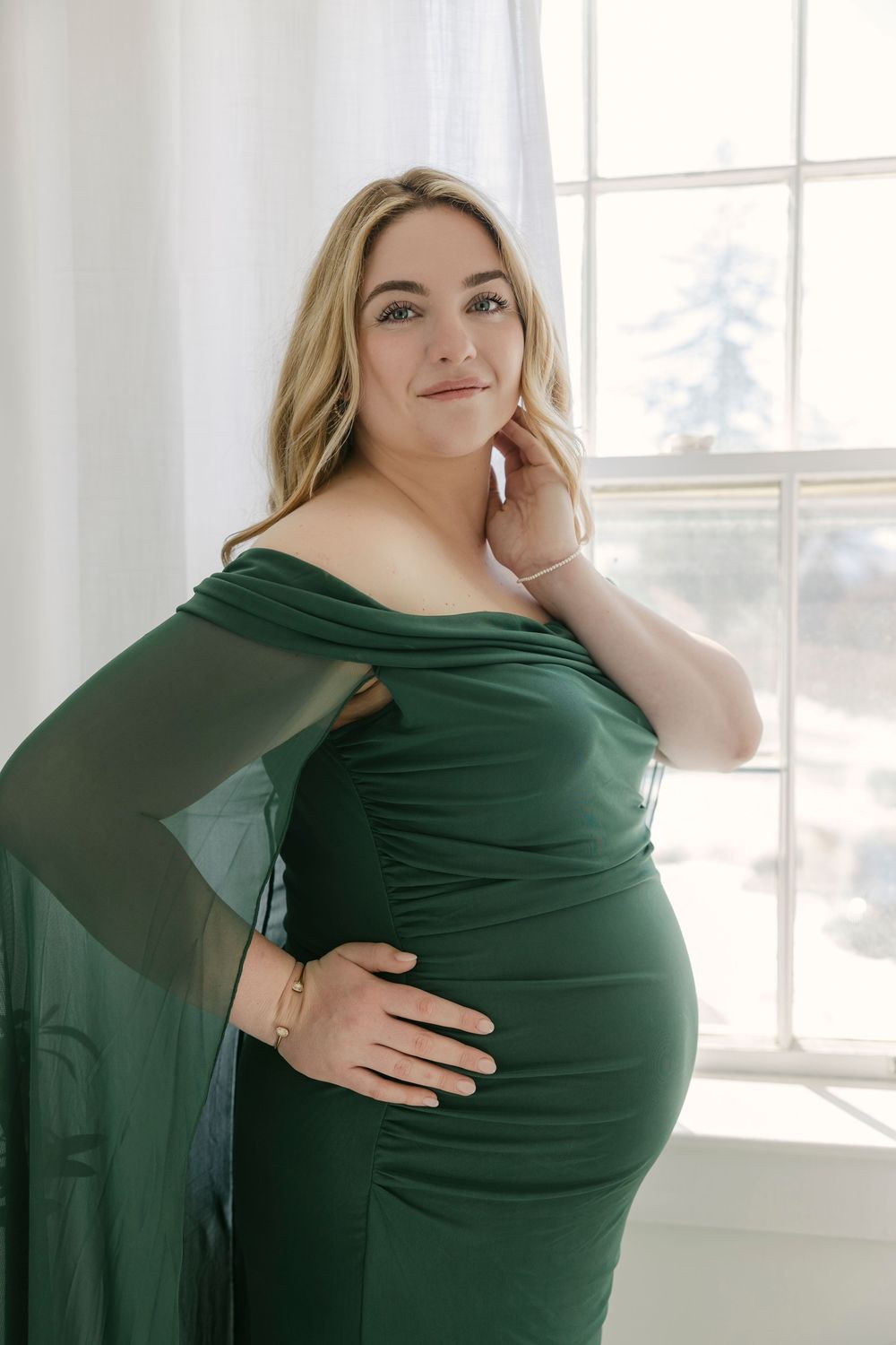 A series of photos showing a person in a dark green top posing against a bright white window background.
