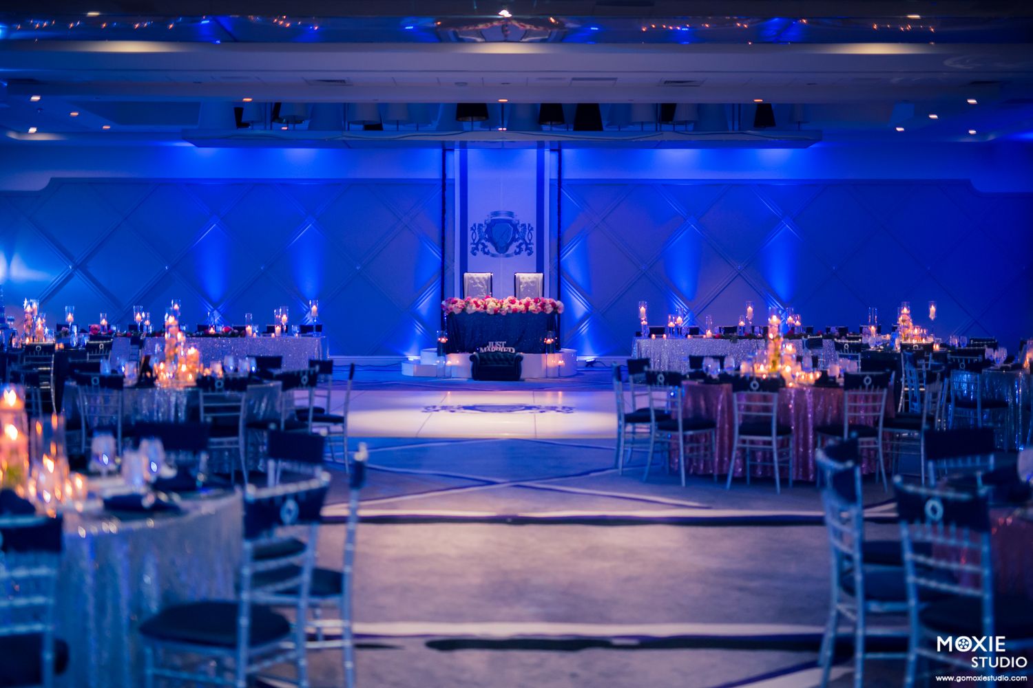 Elegant banquet hall with blue uplighting, round tables, and a glowing stage centerpiece for a formal event at Sahara Las Vegas.