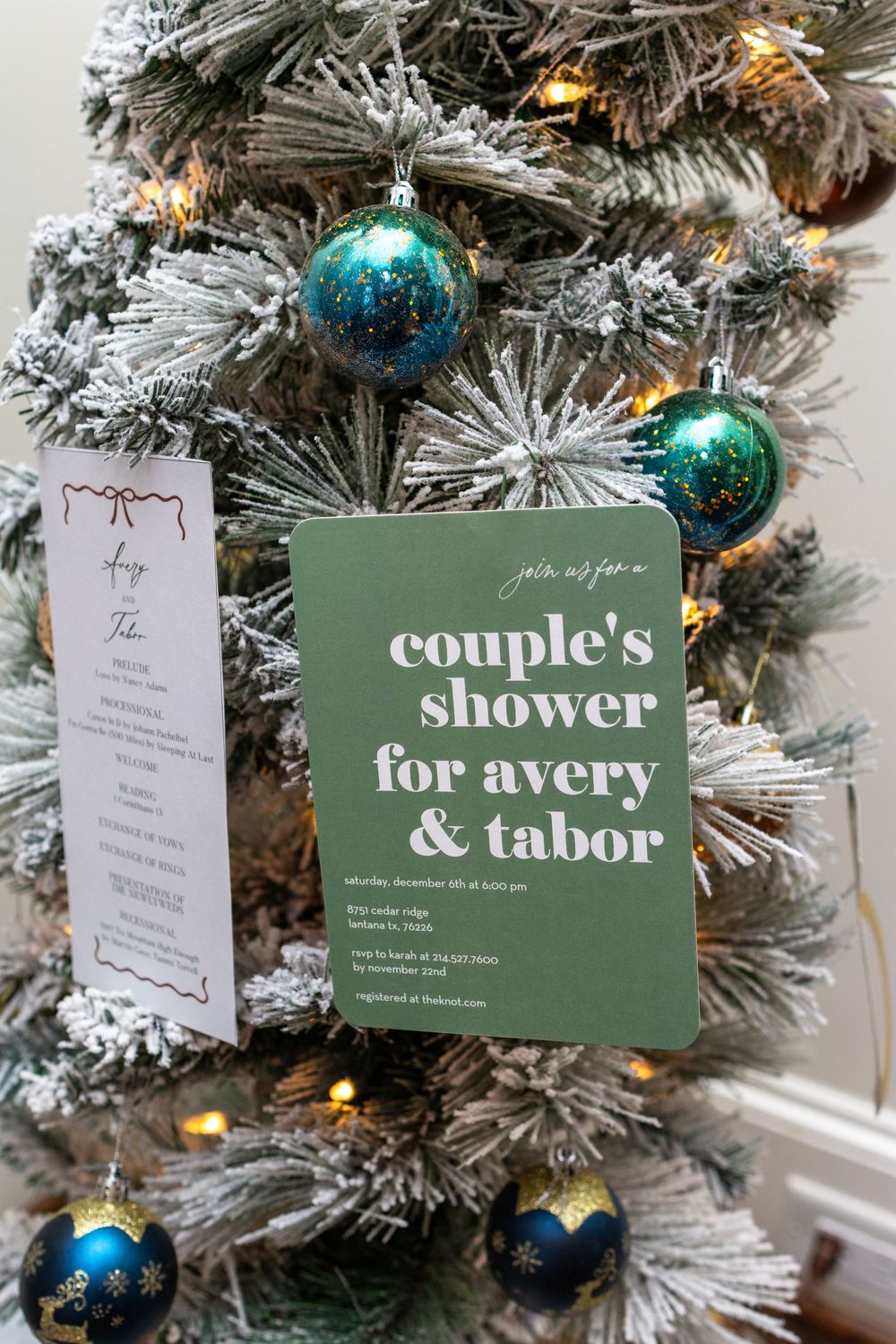 Holiday cards and gift tags hang from a white flocked Christmas tree decorated with blue and teal ornaments.
