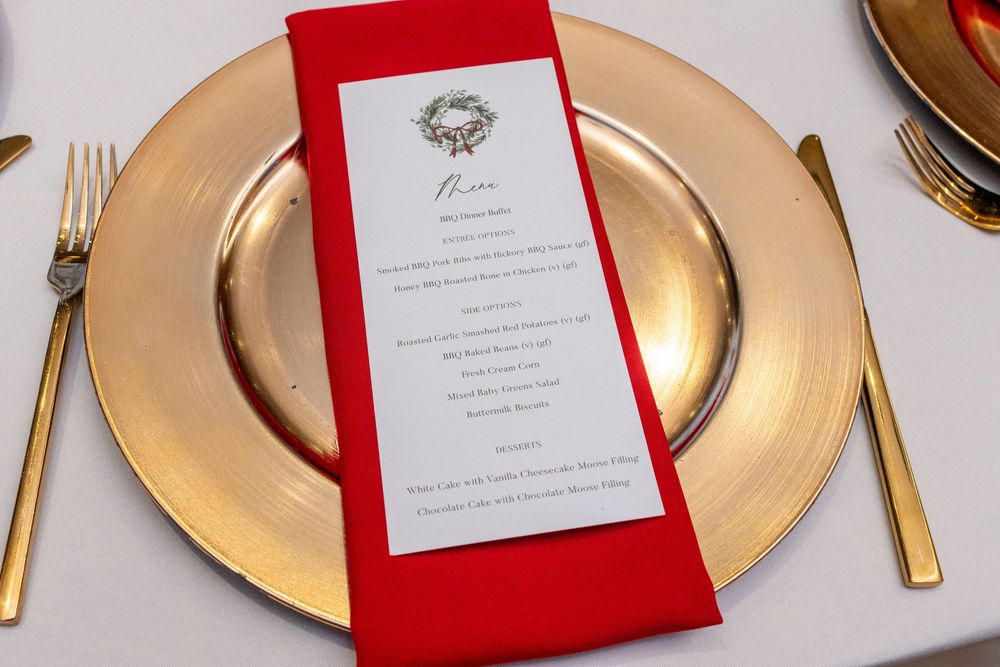 Elegant table setting with gold charger plates, red napkins, and menu cards at a formal dining event.