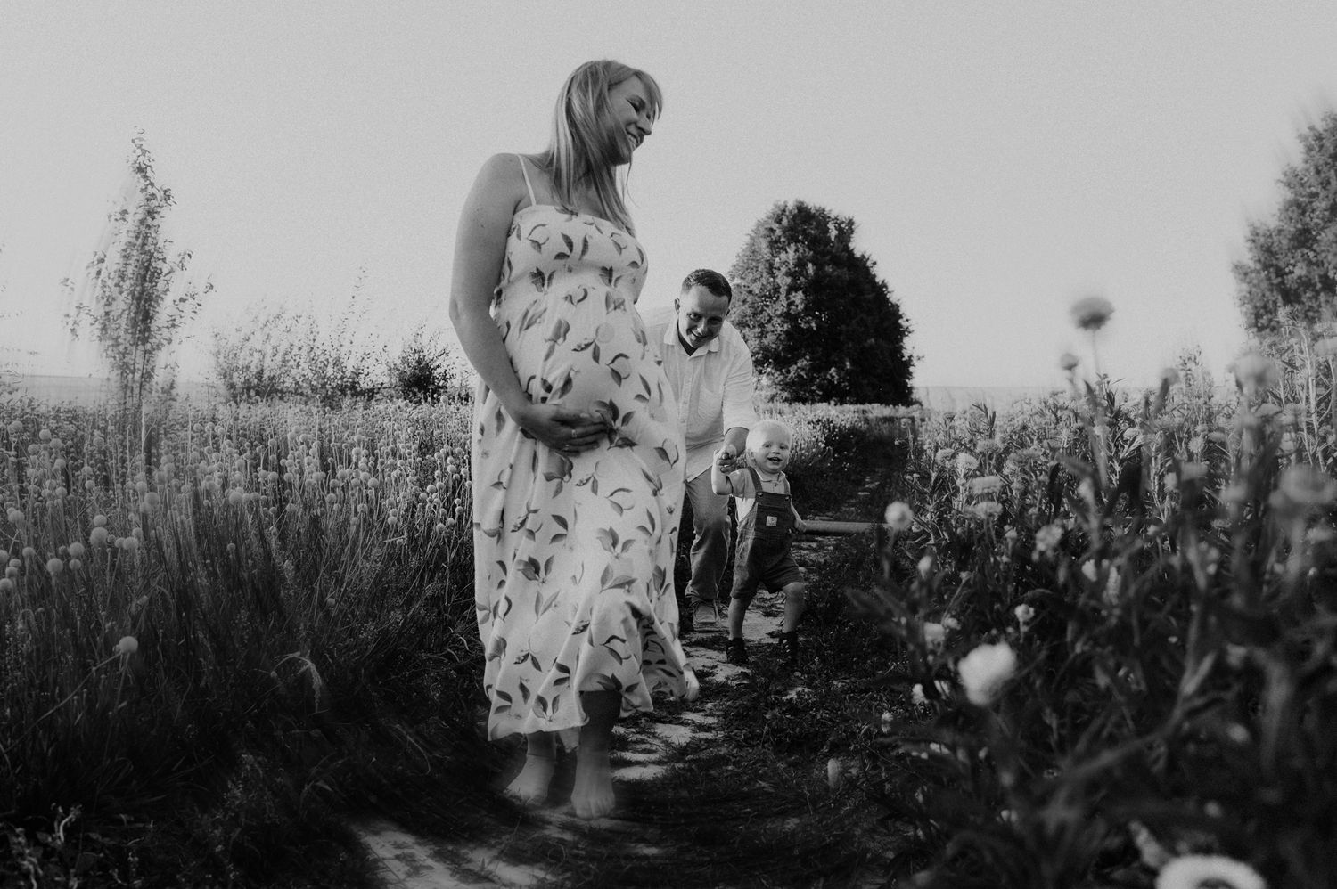 A joyful black and white photograph showing people lying in grass together with arms raised during a sunny day.