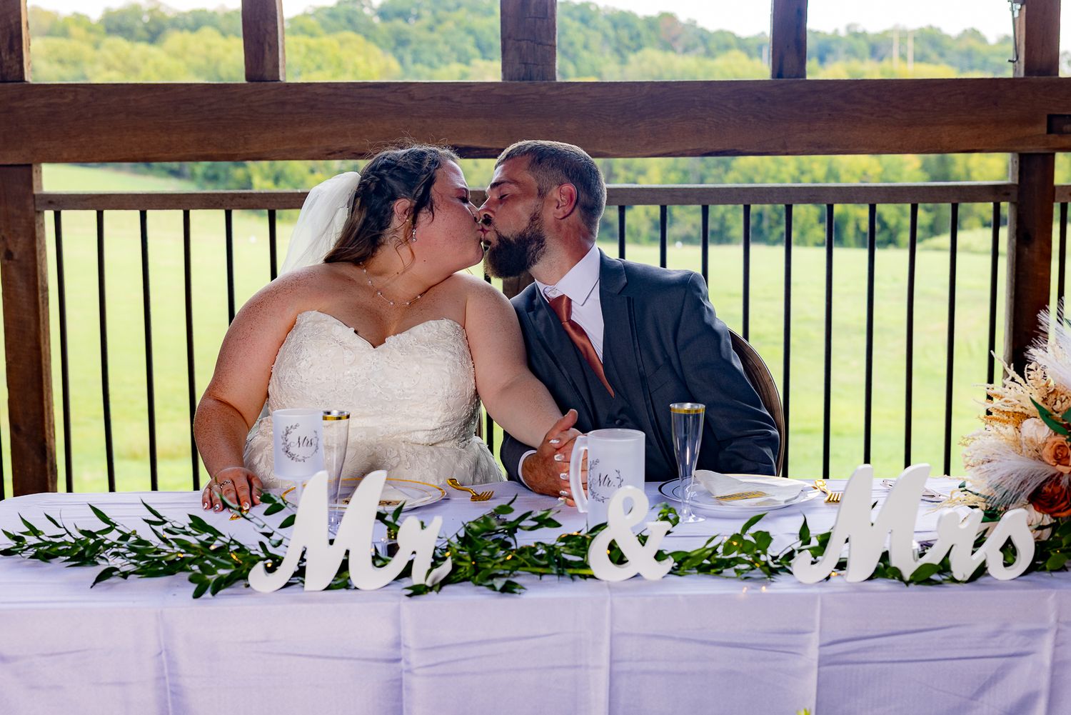 Frederick Maryland Wedding Photographer  Wedding couple sits intimately at reception table with Mr and Mrs decor and greenery.