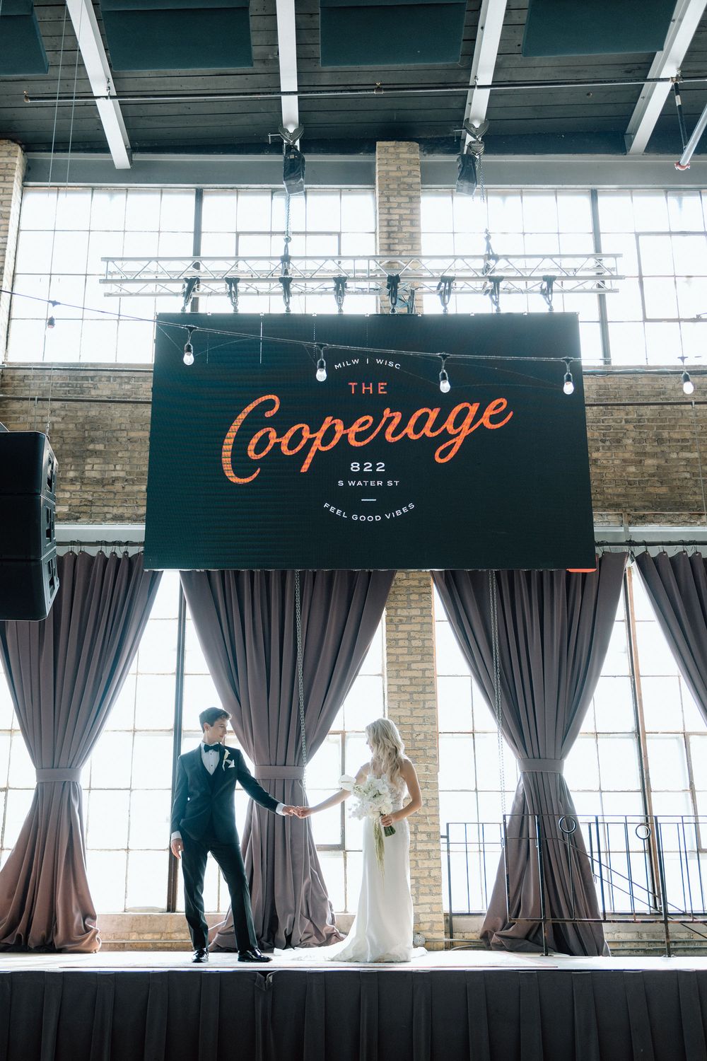 Wedding ceremony setup at The Cooperage venue with dramatic grey curtains and industrial-chic exposed brick walls.