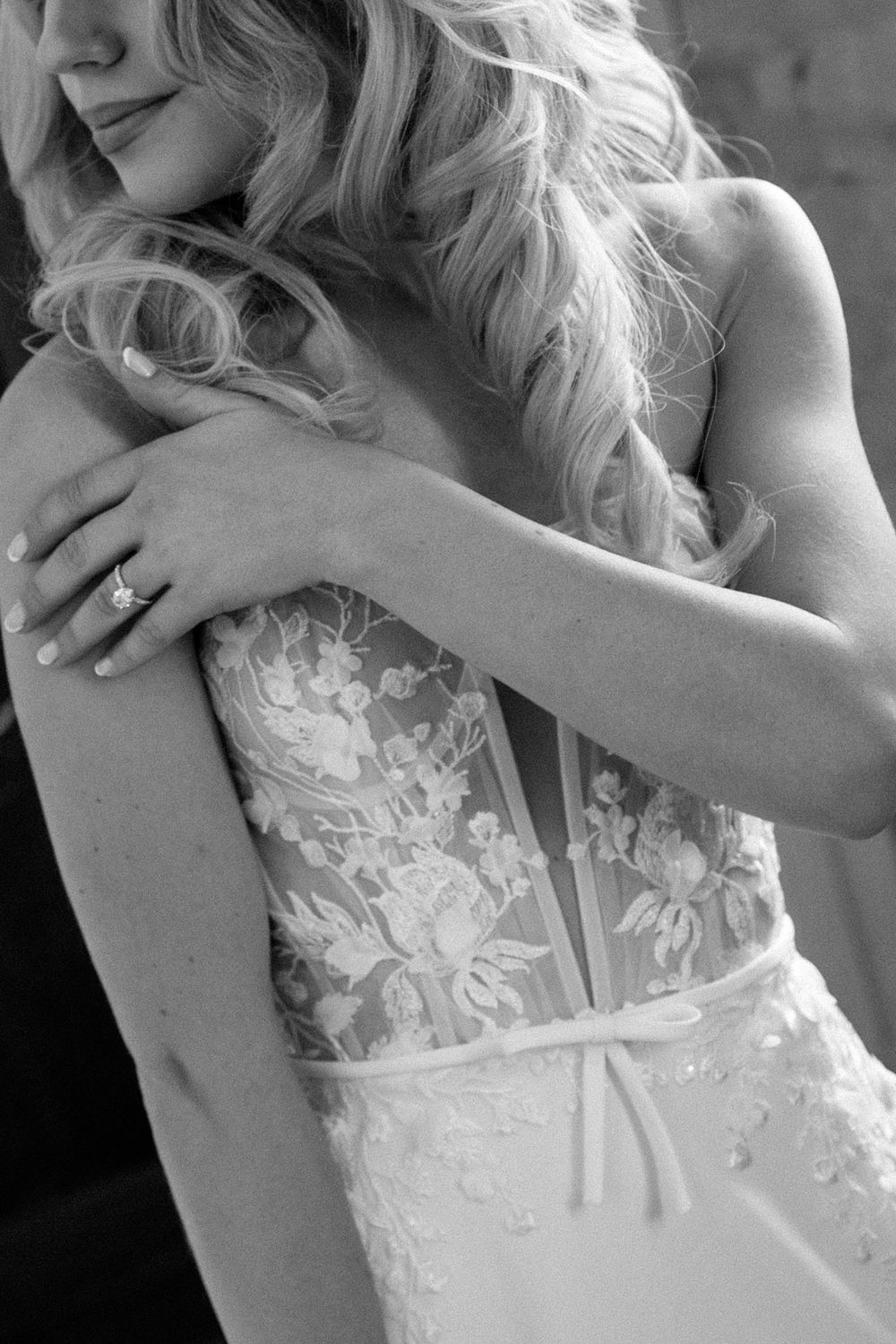 Close-up details of a delicate white lace wedding dress bodice with intricate floral embroidery.