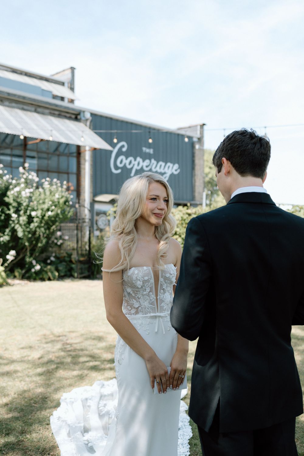 Outdoor wedding scene with greenery and rustic shipping containers in the background.