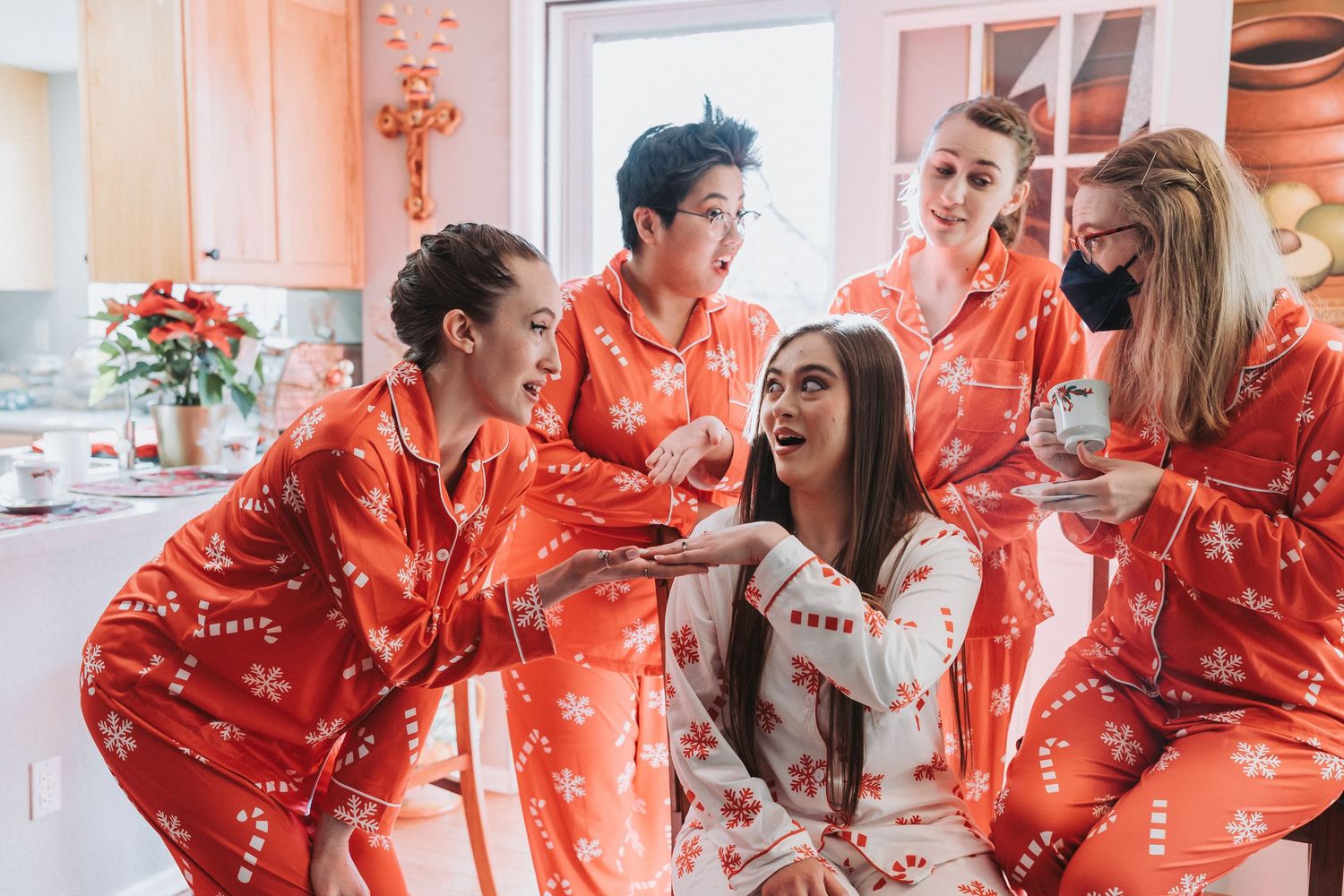 A group wearing matching red satin robes laughs together while getting ready for a special occasion.