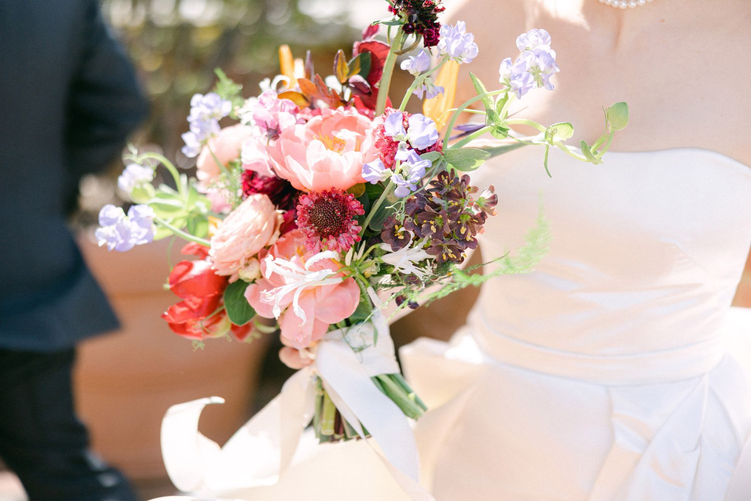 A delicate floral arrangement featuring pink and white blooms with greenery in a glass vase on a table.