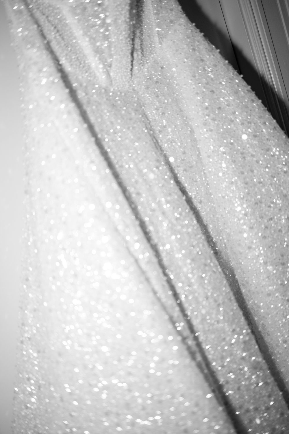 Close-up detail shot of glittering fabric texture on a white wedding dress.