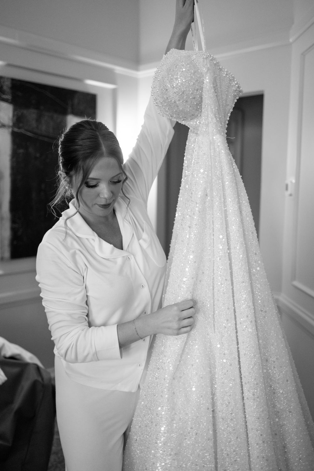 Series of black and white photos showing a wedding dress being prepared and handled with care.