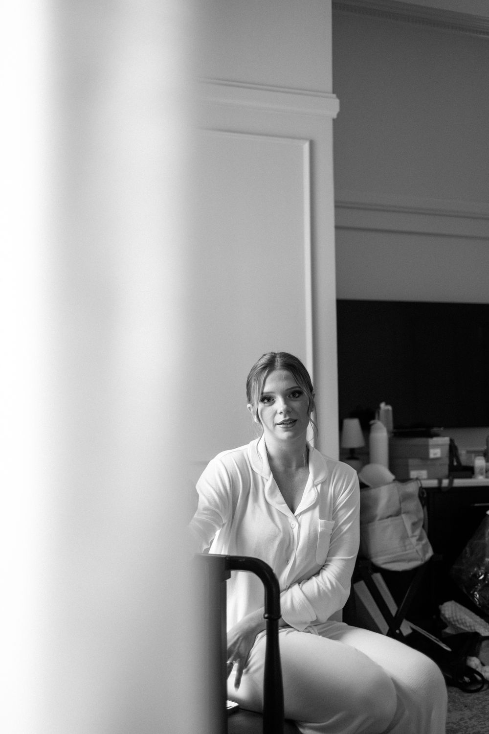 Person in white shirt sitting in a bright room with white columns and walls.
