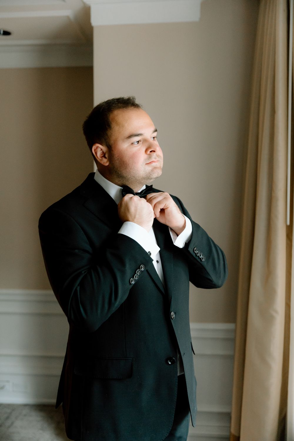 A sequence of photos showing a person in a black suit adjusting their tie and collar in preparation.