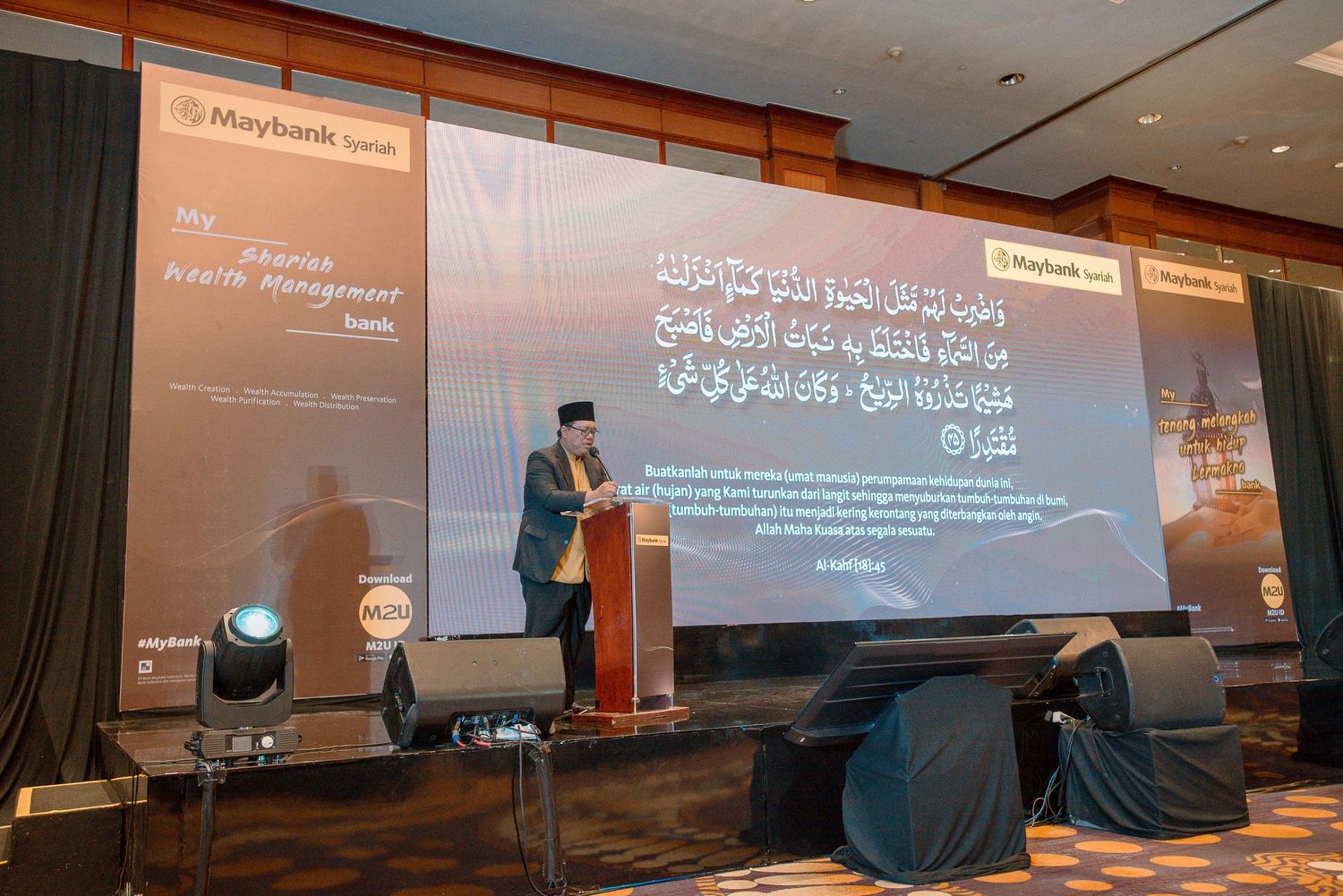 Conference presentation setup with projection screens displaying Arabic text in a dimly lit auditorium.