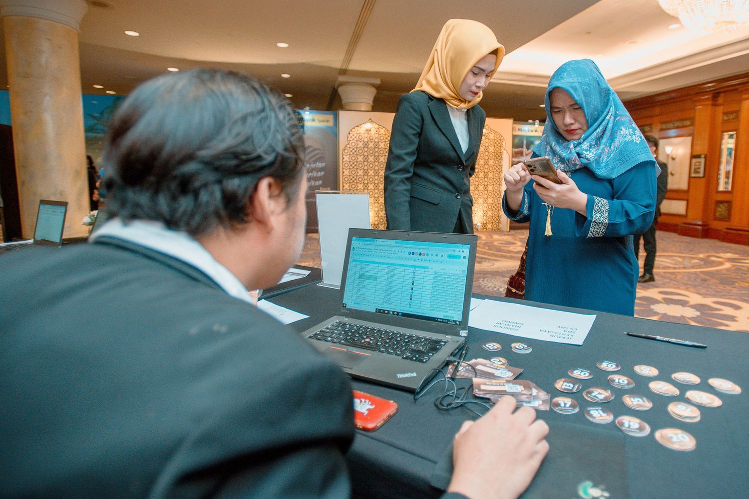 People in business attire gather around tables working on group activities during a professional event.