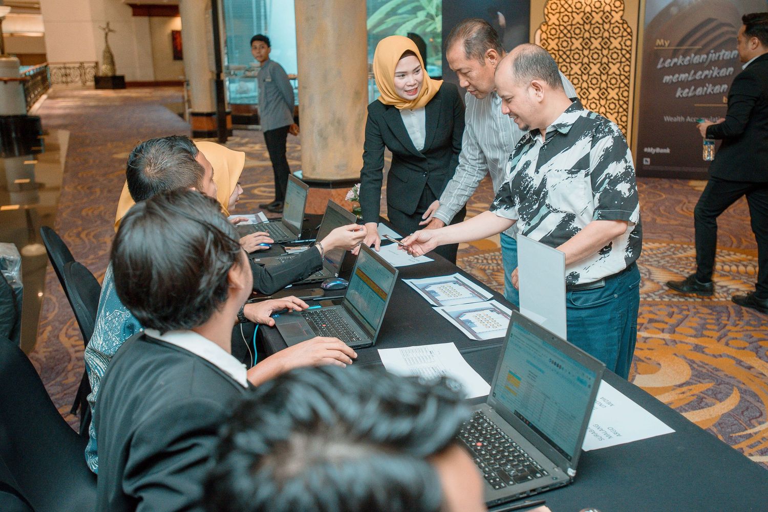 People working together at tables with laptops and documents during a professional business meeting or workshop session.