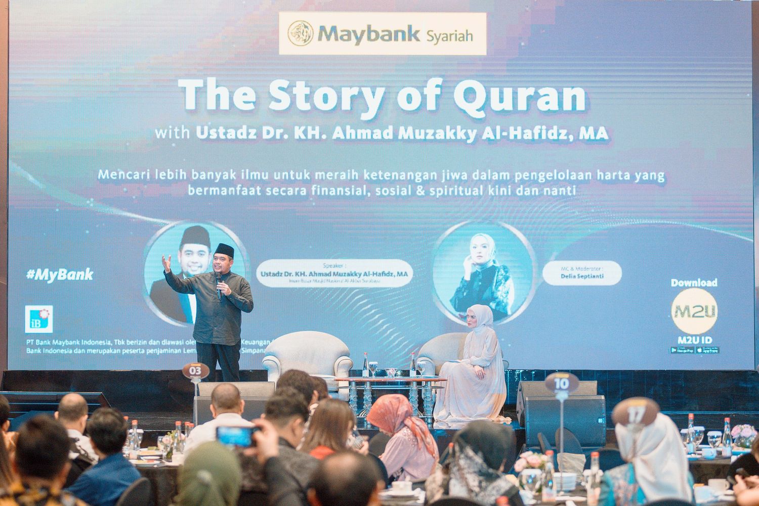 Conference attendees gather in an auditorium for 'The Story of Quran' presentation with Maybank Syariah branding displayed.