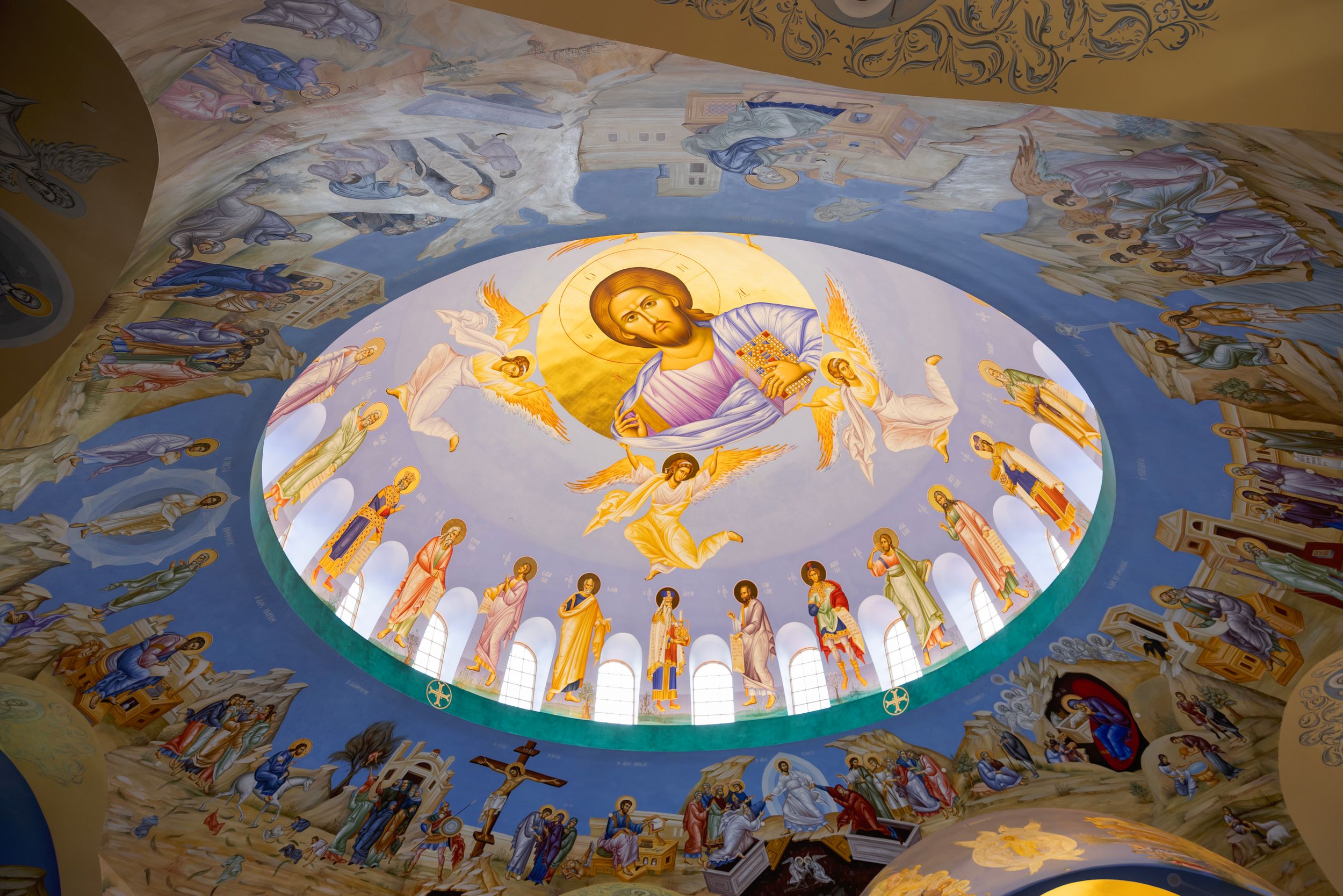 Ornate cathedral ceiling with religious frescoes and golden details painted in a circular dome pattern.