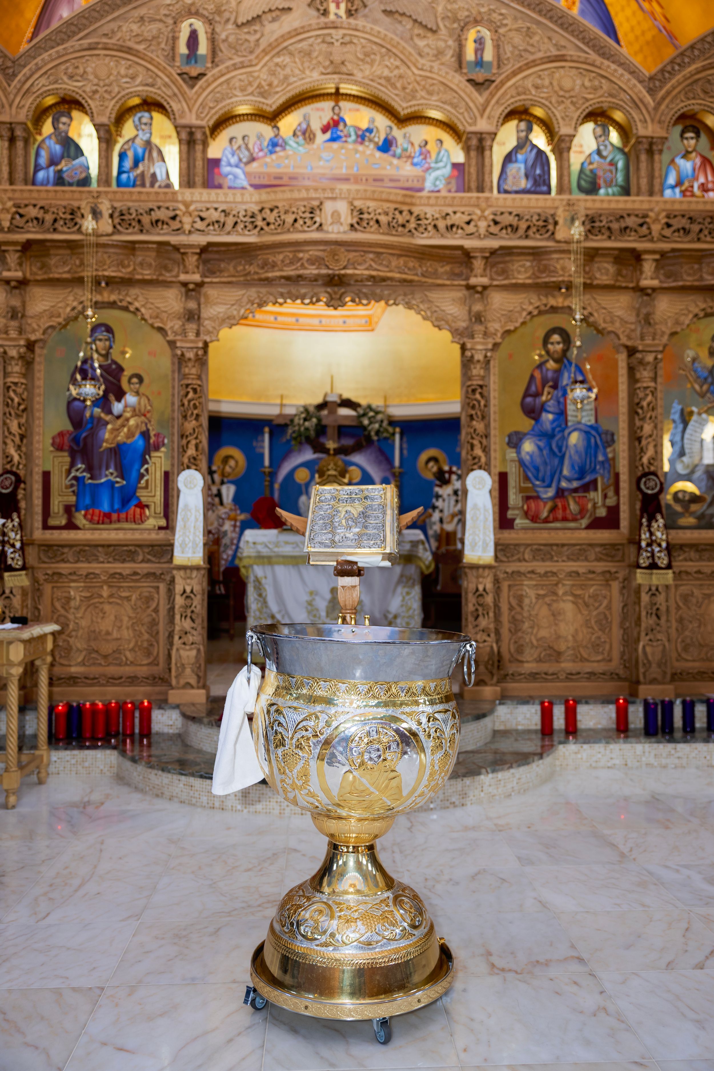 Ornate golden chalice with intricate designs displayed on marble altar in an Orthodox church with religious iconography.