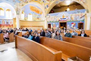 A panoramic view of an ornate church interior with painted murals and wooden pews filled with congregants.