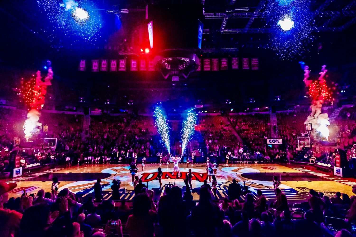 Basketball arena lit up with dramatic red and blue lighting effects during team introduction.