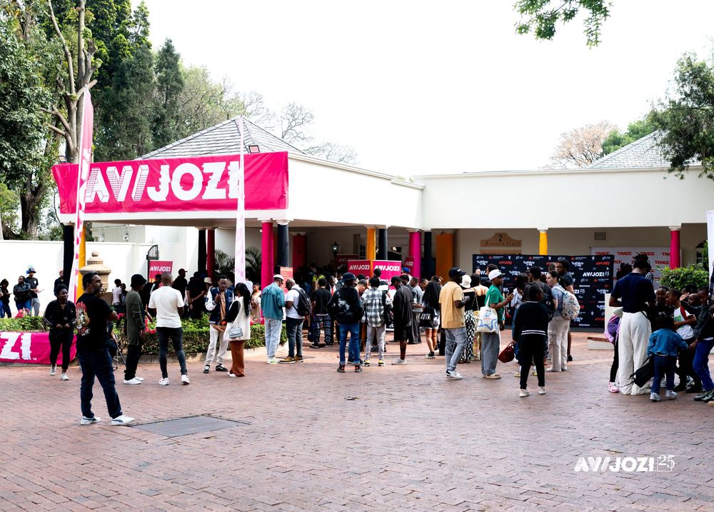 Crowd of people gathering outside entrance of Avaaz event space with pink signage and white tent structure.