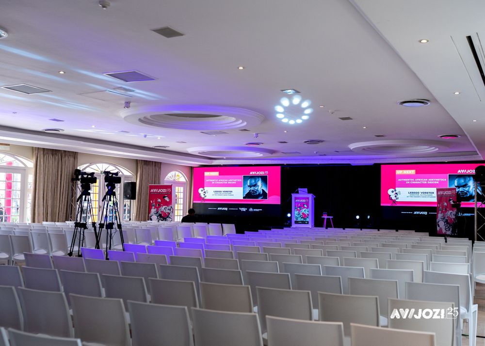 Large conference venue with rows of empty chairs and purple ambient lighting illuminating the space.