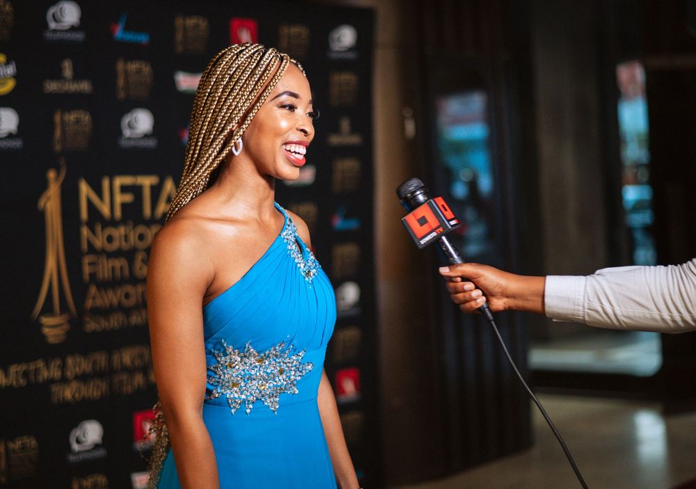 Woman in bright blue formal dress speaks on stage at awards ceremony.
