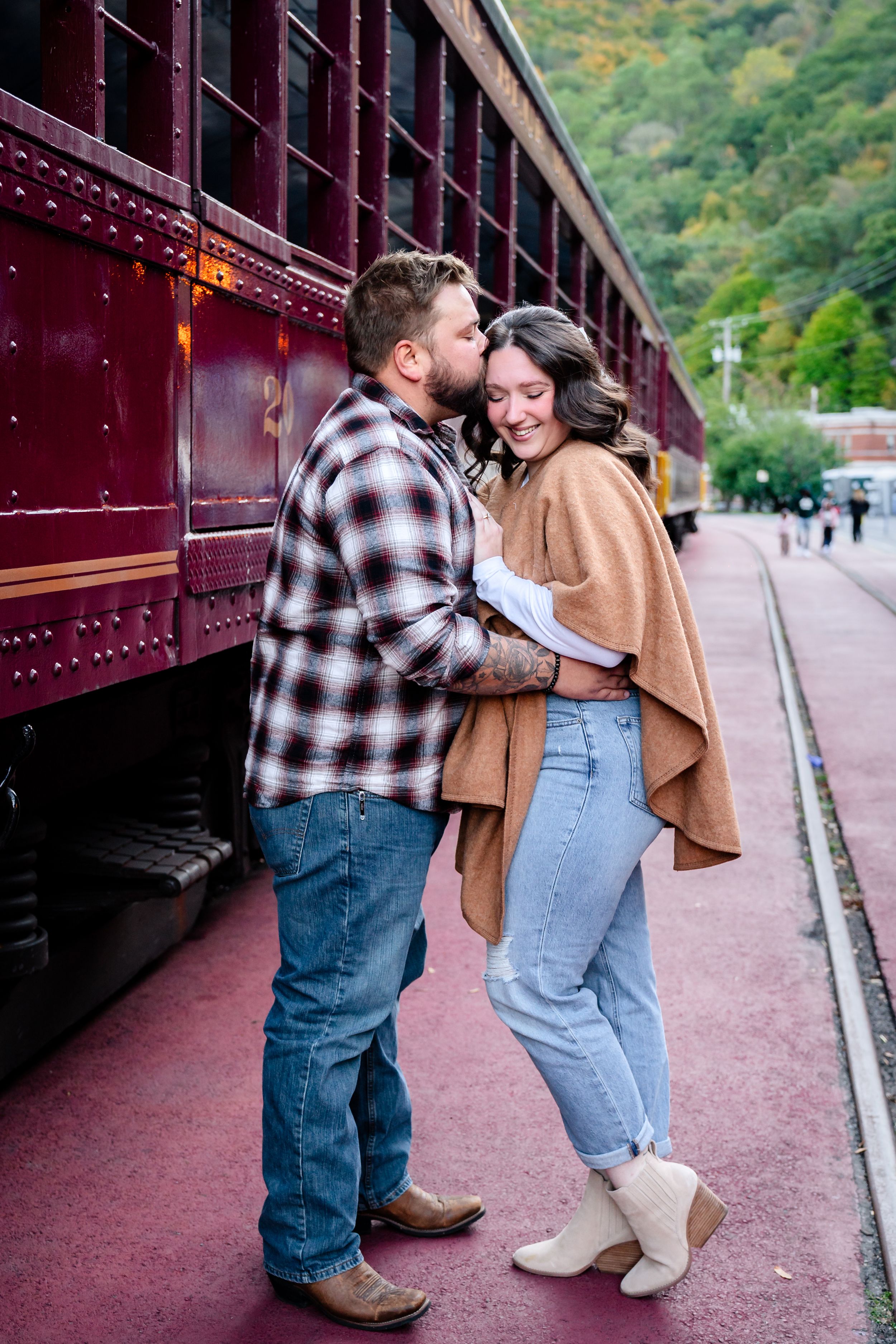 Couple walking together along vintage train platform with mountain backdrop.