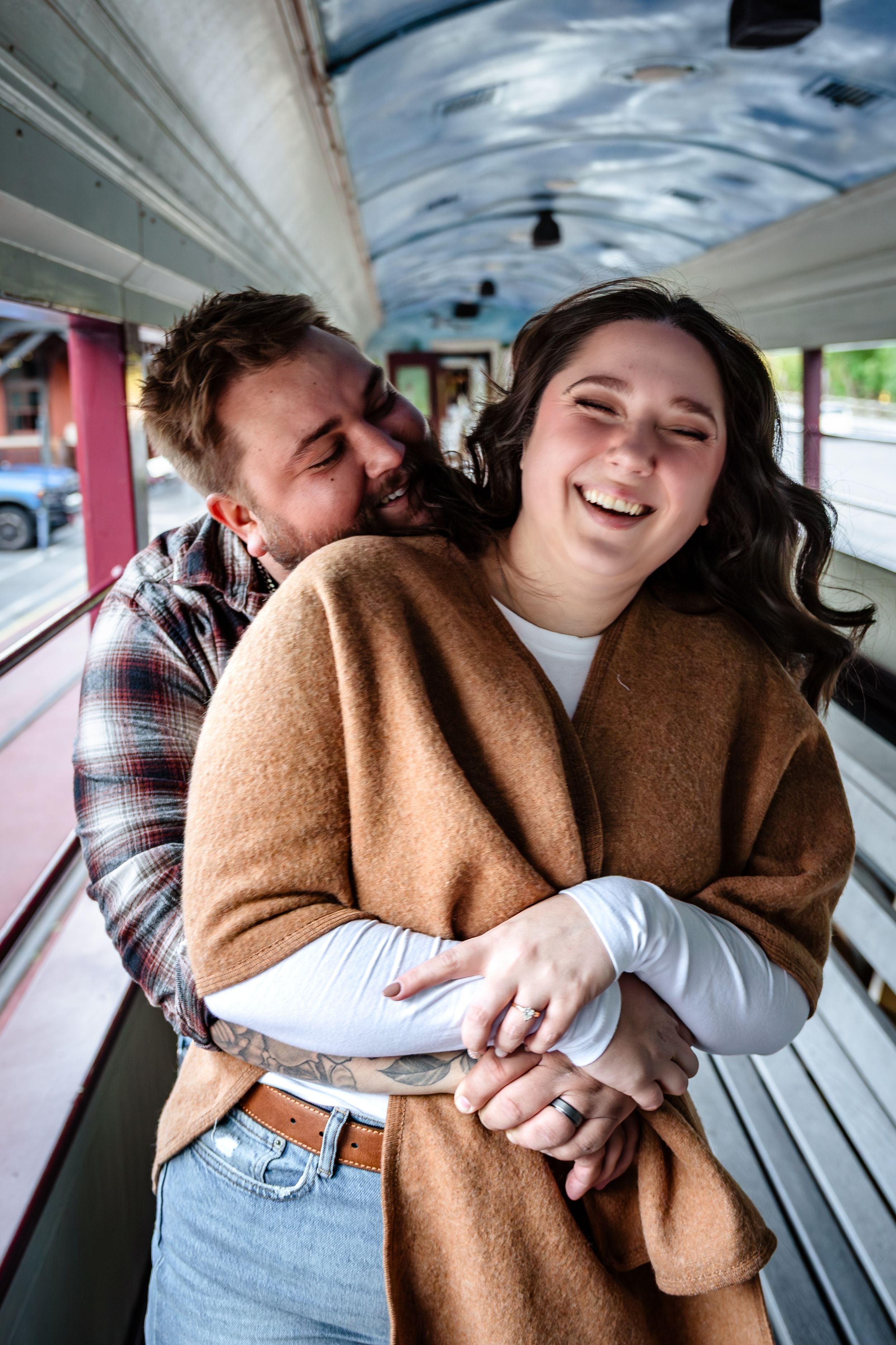 Couple sharing intimate moments on wooden bench wearing casual fall attire.