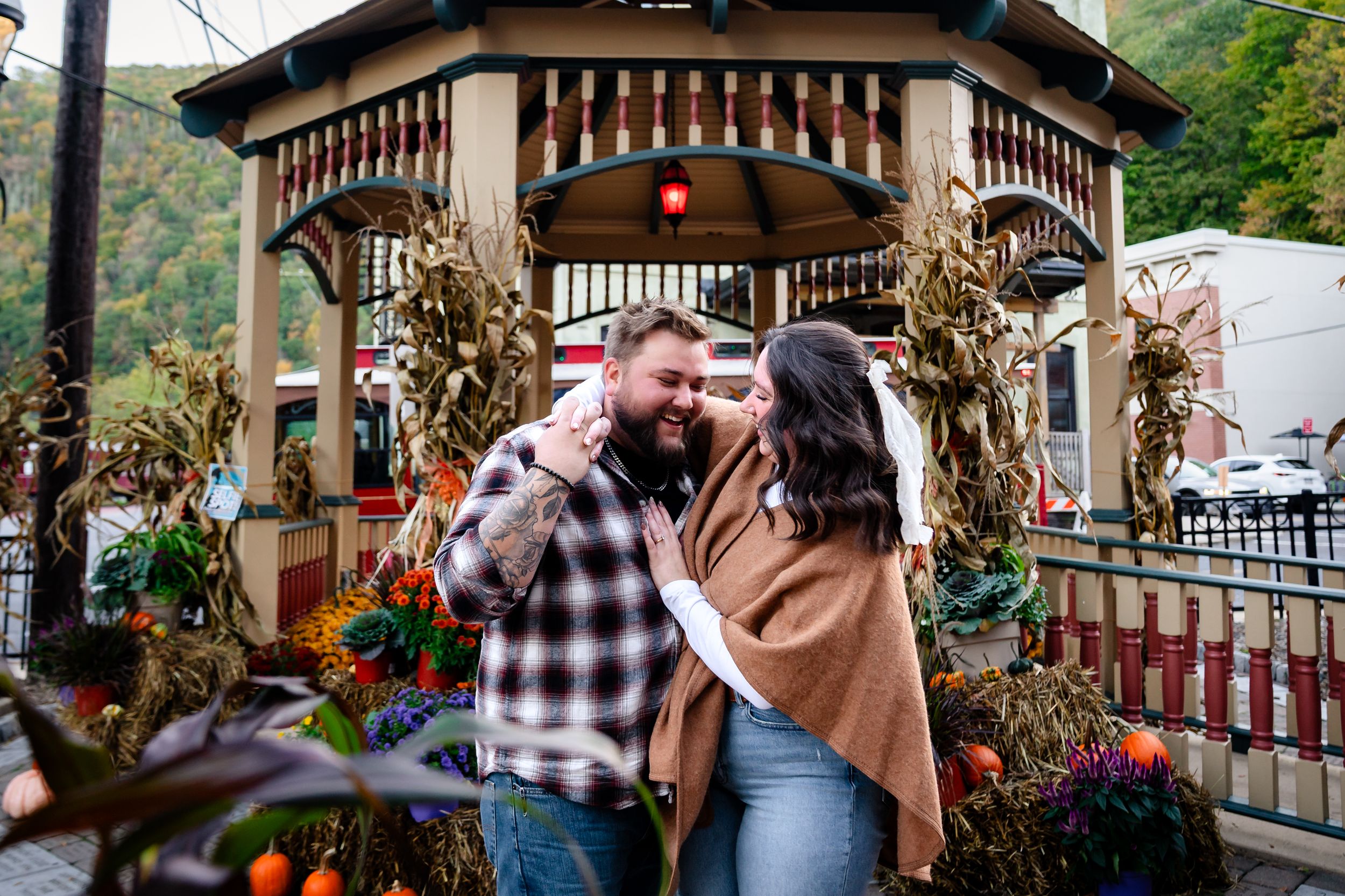 Romantic moment captured at rustic gazebo surrounded by autumn decorations.
