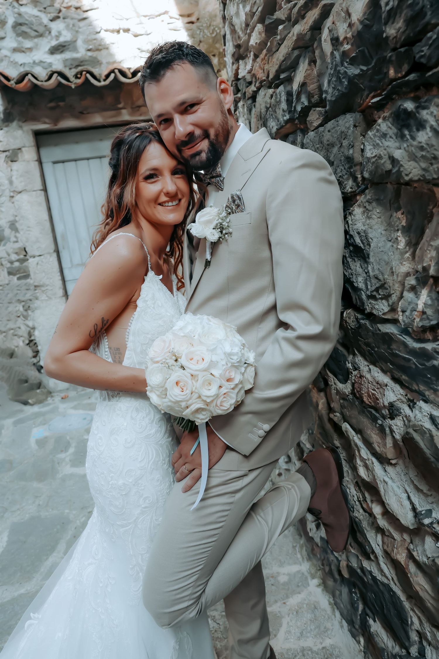 Wedding couple sharing intimate moments against a rustic stone wall.